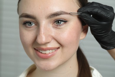 Beautician brushing young woman's eyebrow in beauty salon, closeup