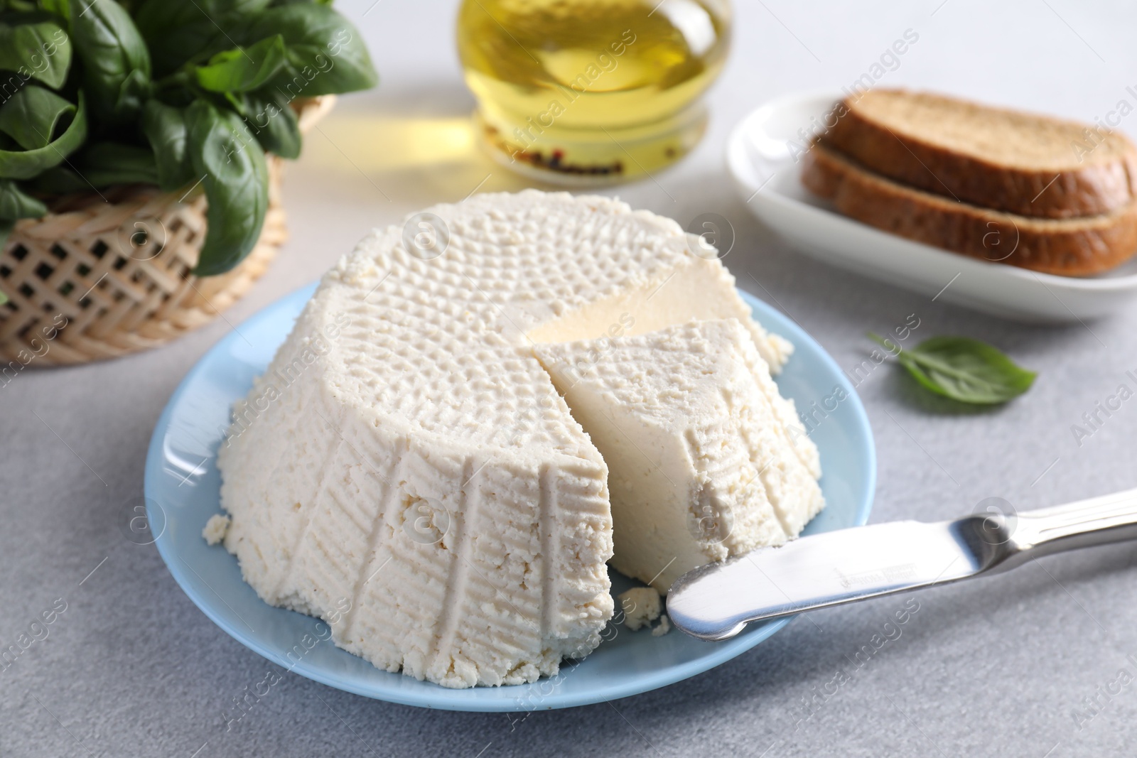 Photo of Tasty ricotta (cream cheese) and knife on grey table