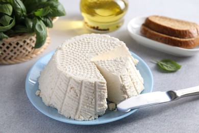 Tasty ricotta (cream cheese) and knife on grey table