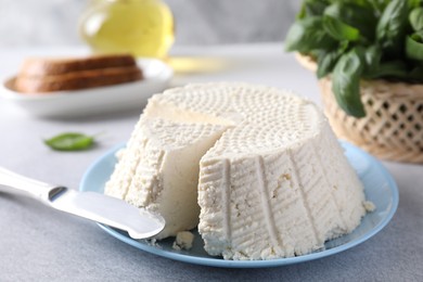 Tasty ricotta (cream cheese) and knife on grey table, closeup