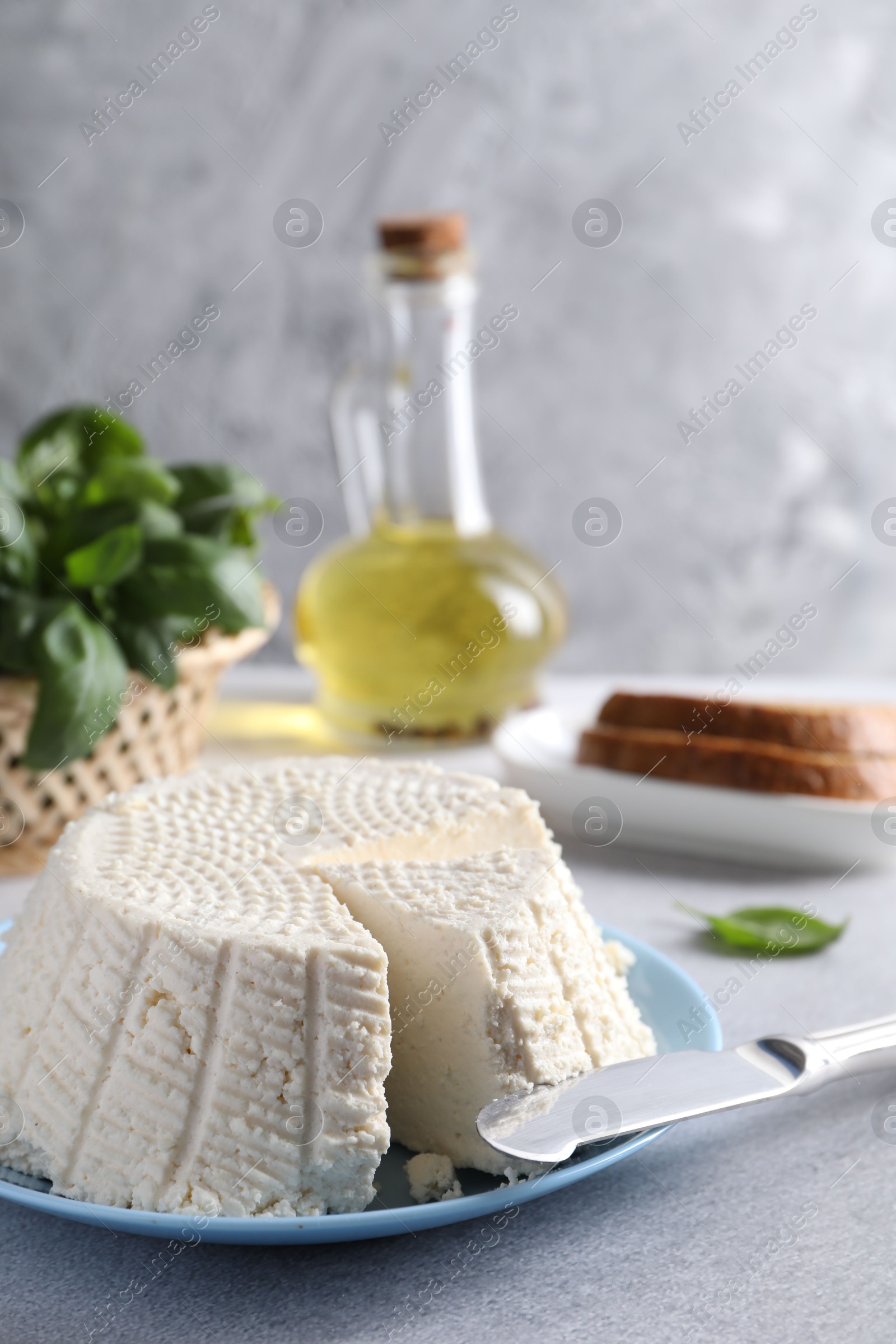 Photo of Tasty ricotta (cream cheese) and knife on grey table, closeup