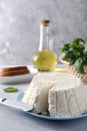 Photo of Tasty ricotta (cream cheese) and knife on grey table, closeup