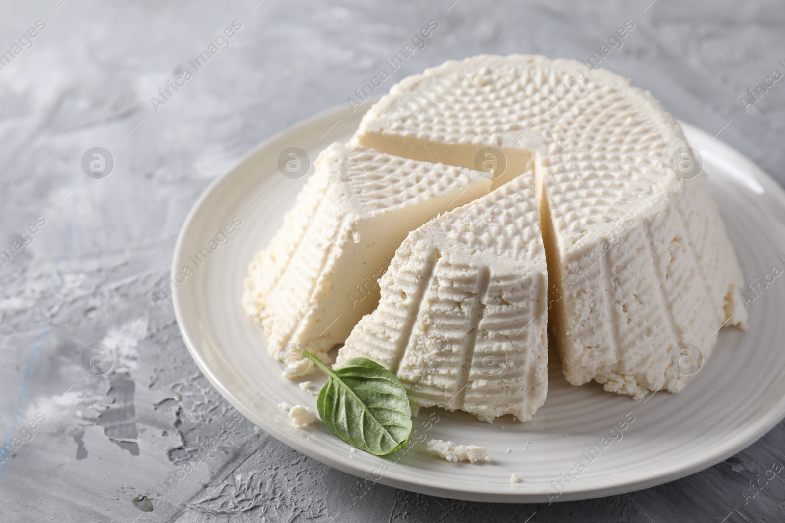 Photo of Tasty ricotta (cream cheese) on grey textured table