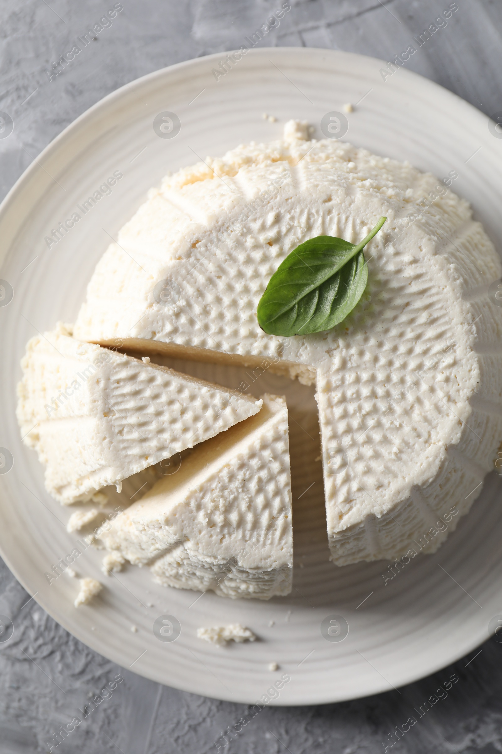 Photo of Tasty ricotta (cream cheese) on grey textured table, top view