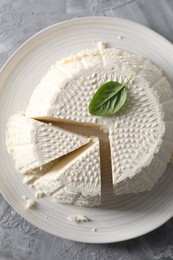 Tasty ricotta (cream cheese) on grey textured table, top view