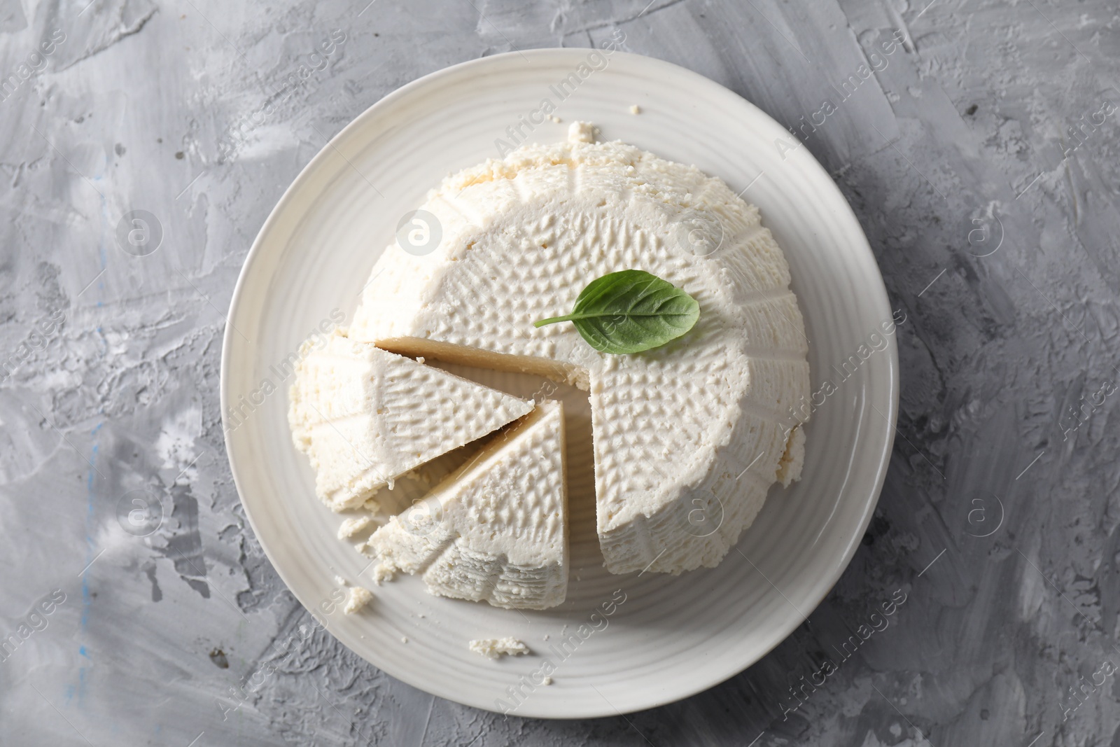 Photo of Tasty ricotta (cream cheese) on grey textured table, top view