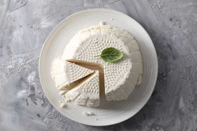 Tasty ricotta (cream cheese) on grey textured table, top view