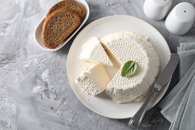 Tasty ricotta (cream cheese), bread and knife on grey table, flat lay