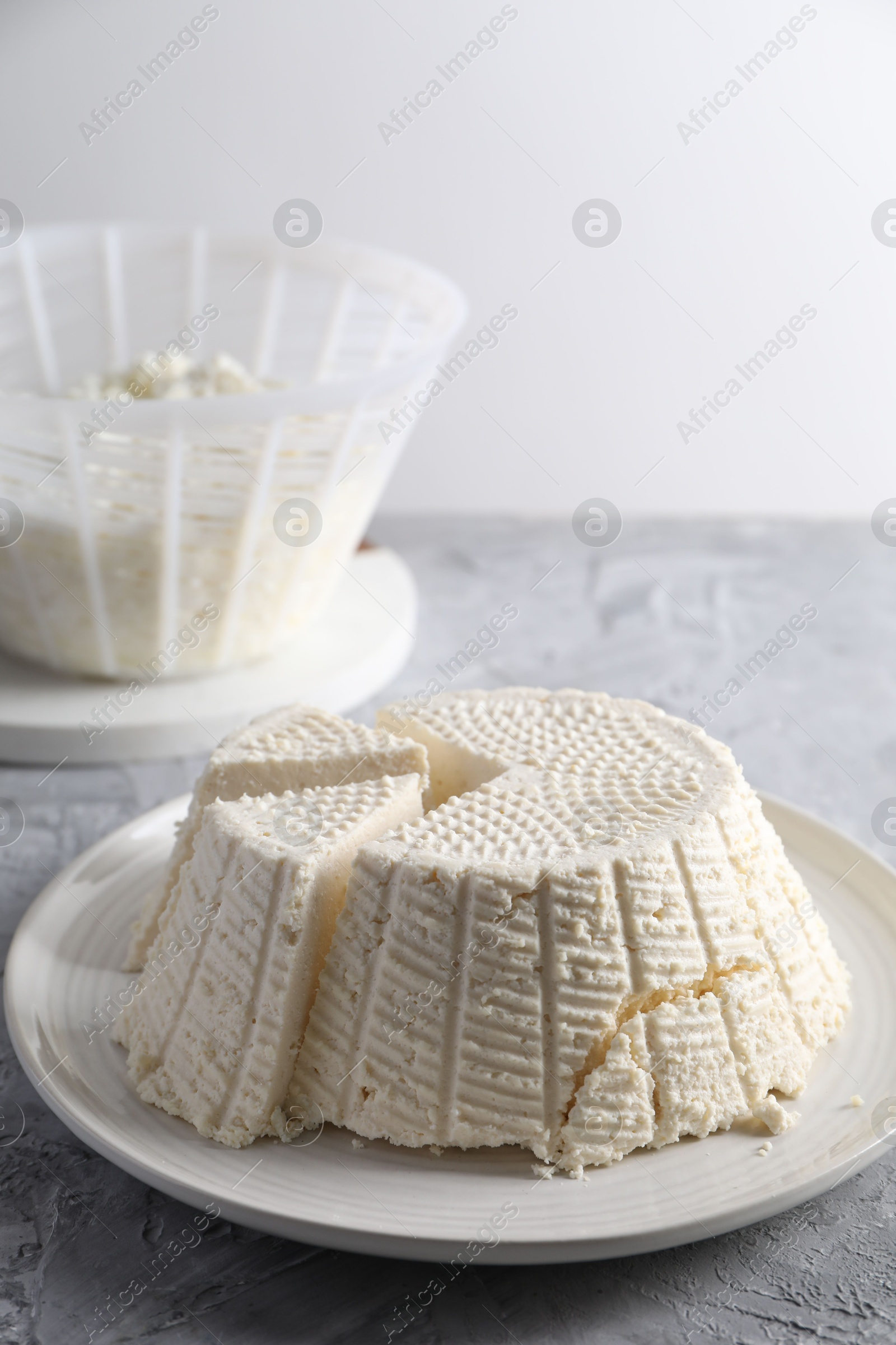 Photo of Tasty ricotta (cream cheese) on grey textured table, closeup