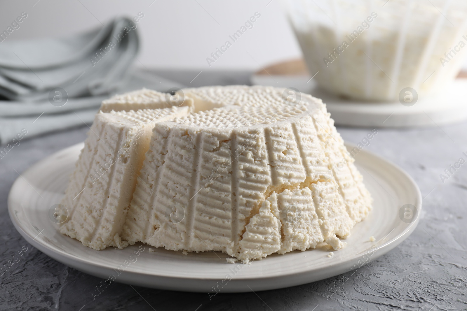 Photo of Tasty ricotta (cream cheese) on grey textured table, closeup