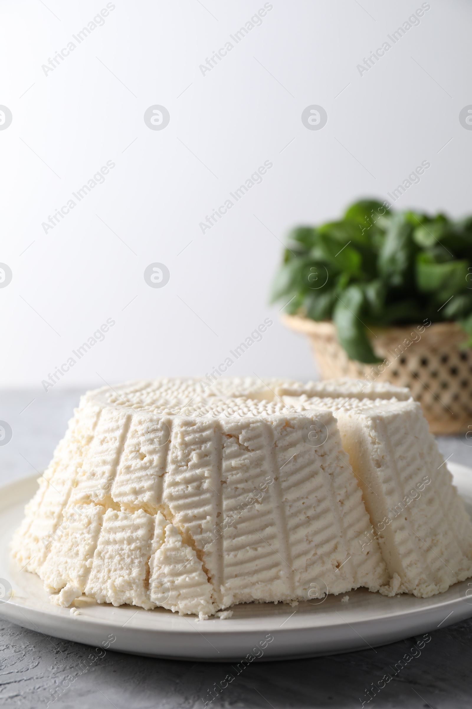 Photo of Tasty ricotta (cream cheese) on grey textured table, closeup