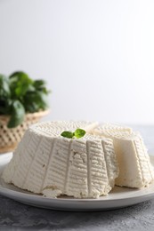 Photo of Tasty ricotta (cream cheese) on grey textured table, closeup