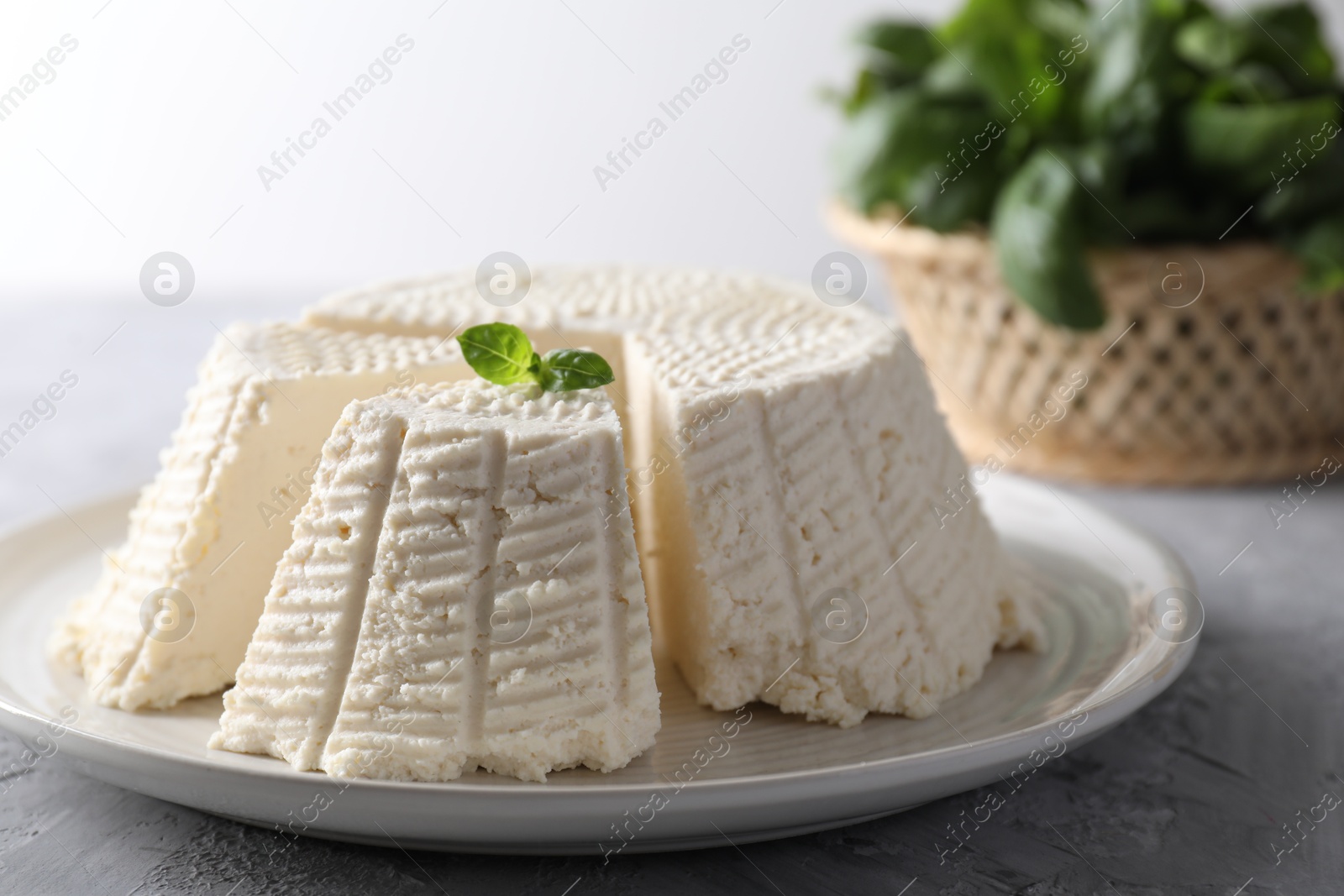 Photo of Tasty ricotta (cream cheese) on grey textured table, closeup