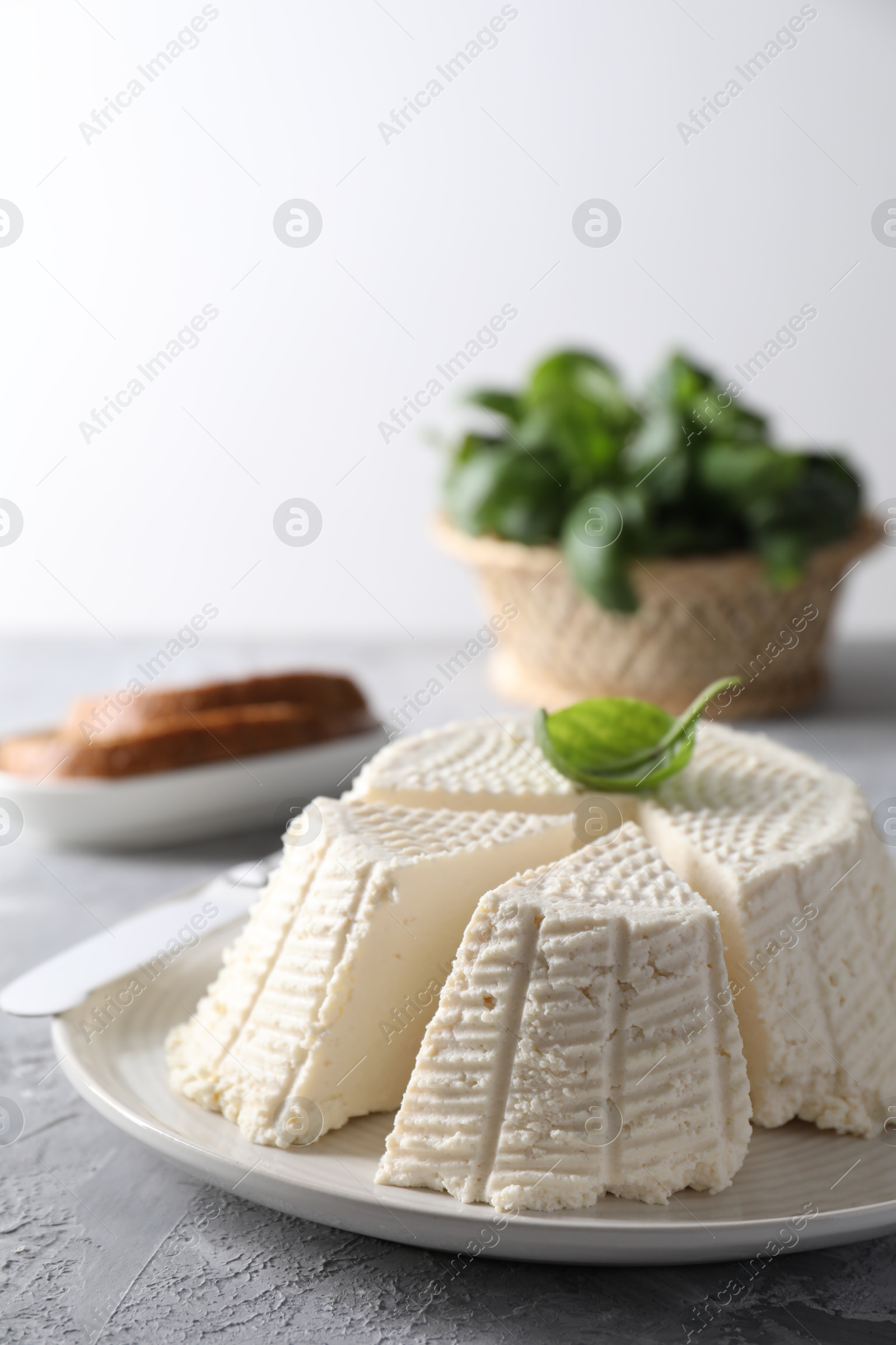 Photo of Tasty ricotta (cream cheese) and knife on grey textured table, closeup