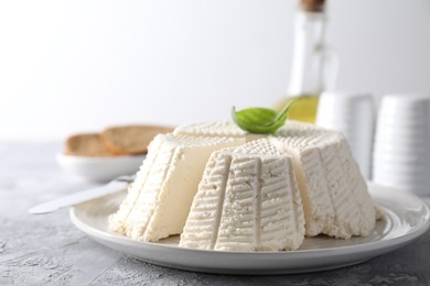 Photo of Tasty ricotta (cream cheese) and knife on grey textured table, closeup