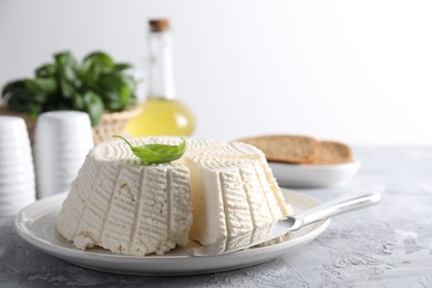 Tasty ricotta (cream cheese) and knife on grey textured table, closeup. Space for text