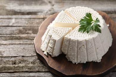 Photo of Tasty ricotta (cream cheese) on wooden table, closeup. Space for text