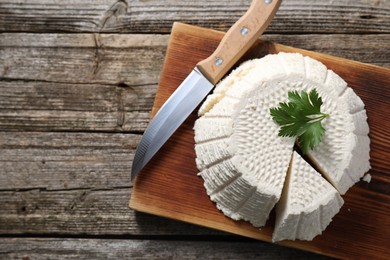 Tasty ricotta (cream cheese) and knife on wooden table, top view. Space for text