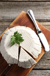 Tasty ricotta (cream cheese) and knife on wooden table, top view