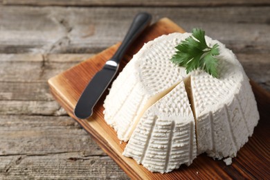 Tasty ricotta (cream cheese) and knife on wooden table, closeup