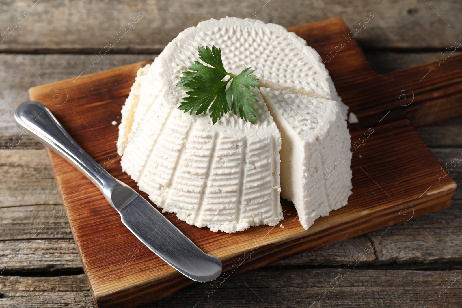 Photo of Tasty ricotta (cream cheese) and knife on wooden table