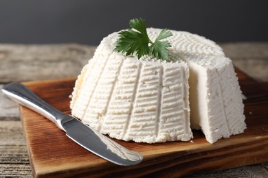 Tasty ricotta (cream cheese) and knife on wooden table, closeup