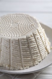 Tasty ricotta (cream cheese) on white wooden table, closeup