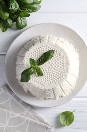 Tasty ricotta (cream cheese) and basil on white wooden table, flat lay