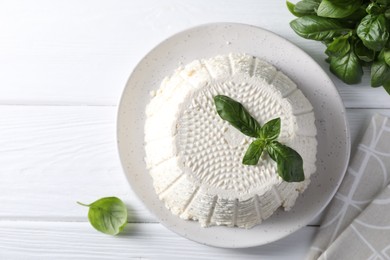 Photo of Tasty ricotta (cream cheese) and basil on white wooden table, flat lay. Space for text