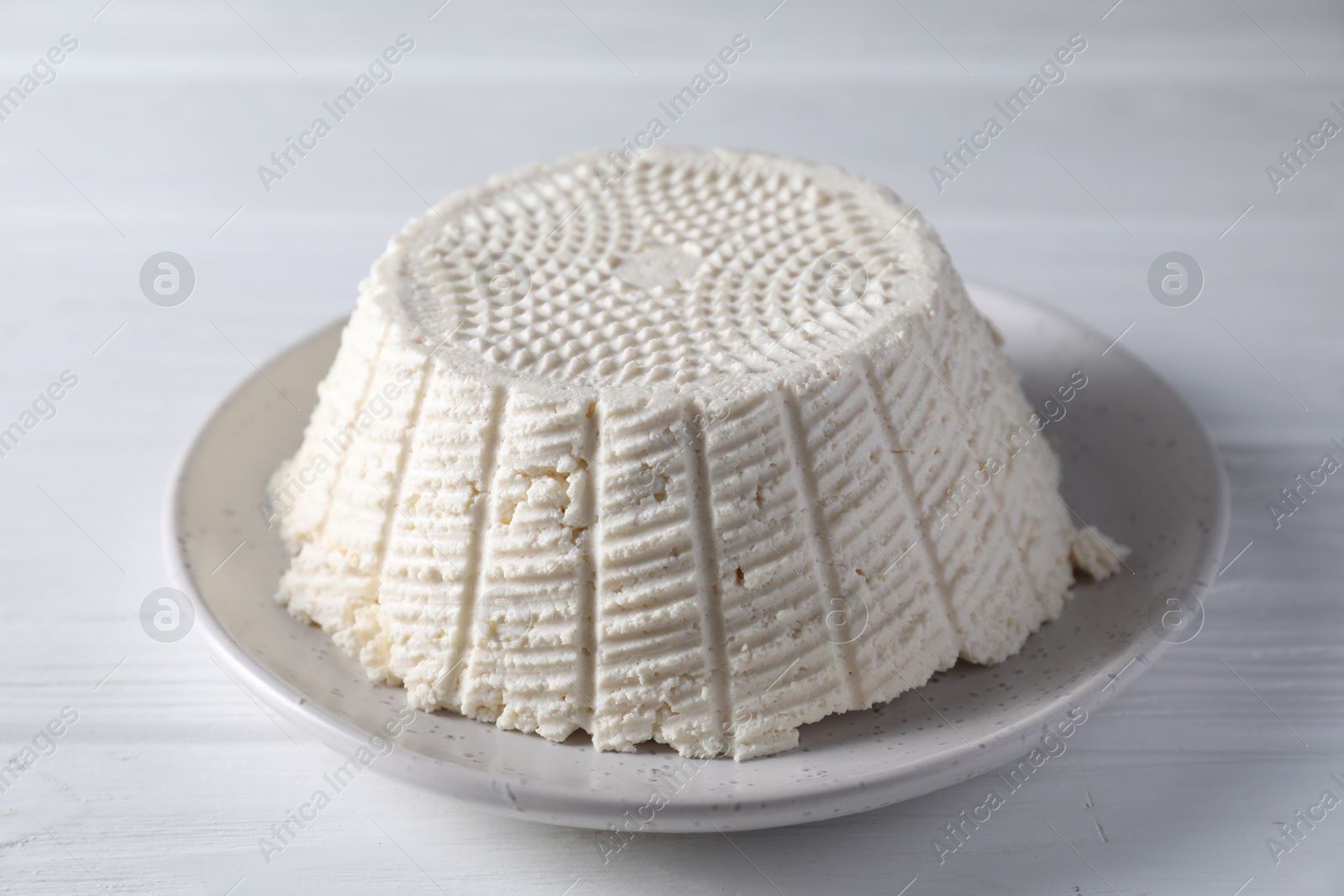 Photo of Tasty ricotta (cream cheese) on white wooden table