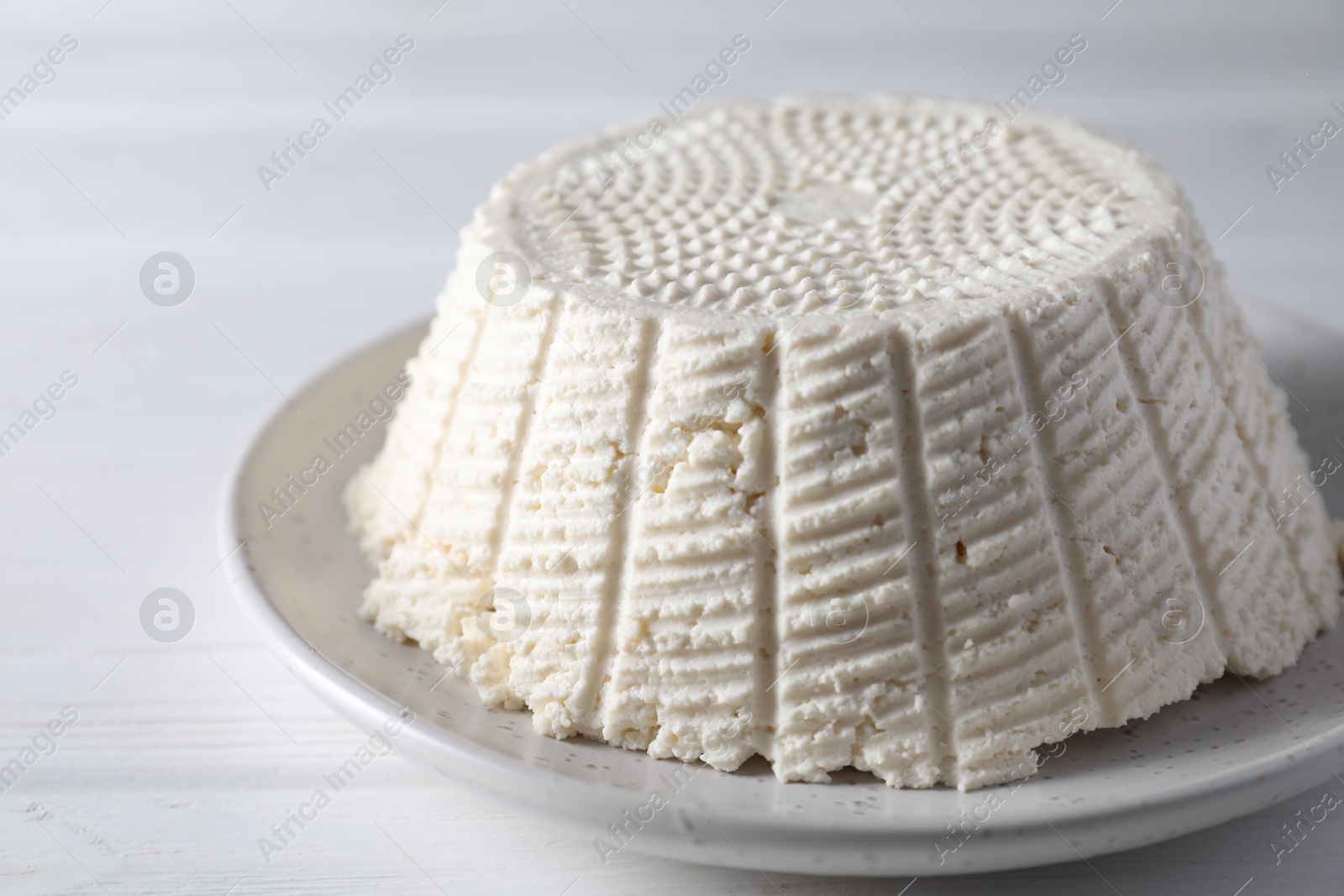 Photo of Tasty ricotta (cream cheese) on white wooden table, closeup