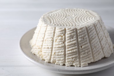 Tasty ricotta (cream cheese) on white wooden table, closeup