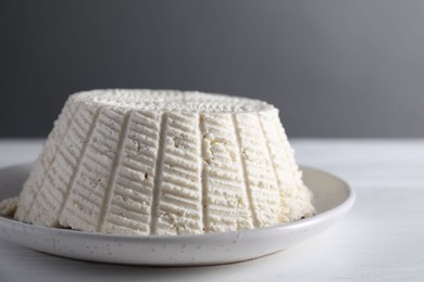 Photo of Tasty ricotta (cream cheese) on white wooden table, closeup