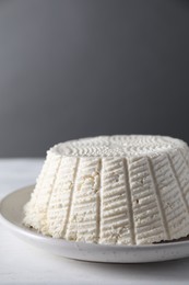 Photo of Tasty ricotta (cream cheese) on white wooden table, closeup