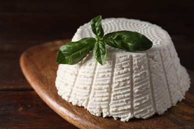 Tasty ricotta (cream cheese) and basil on wooden table, closeup