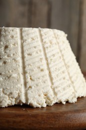 Photo of Tasty ricotta (cream cheese) on wooden table, closeup