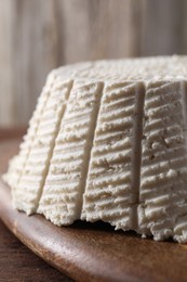 Photo of Tasty ricotta (cream cheese) on wooden table, closeup