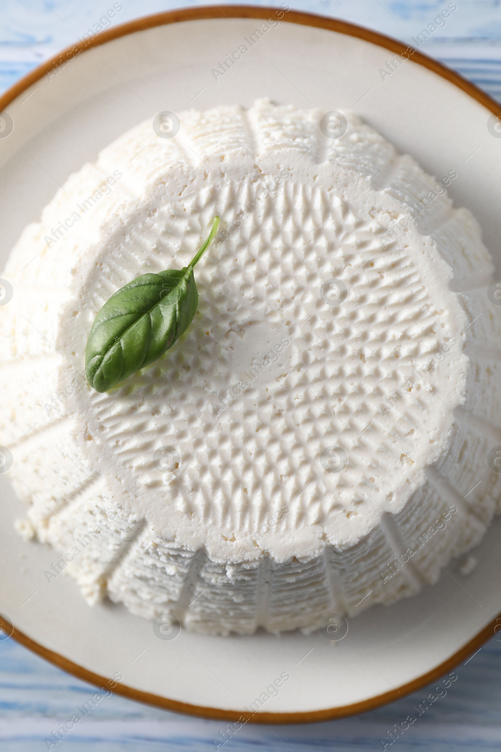 Photo of Tasty ricotta (cream cheese) on light blue wooden table, top view