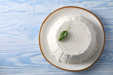 Photo of Tasty ricotta (cream cheese) on light blue wooden table, top view. Space for text