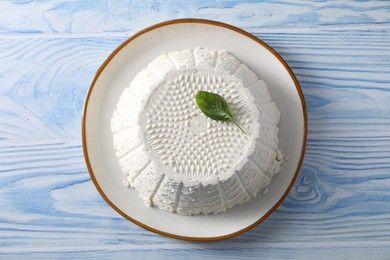 Tasty ricotta (cream cheese) on light blue wooden table, top view