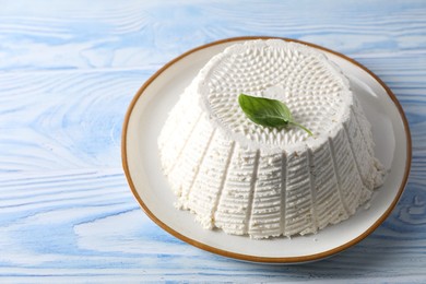 Photo of Tasty ricotta (cream cheese) on light blue wooden table