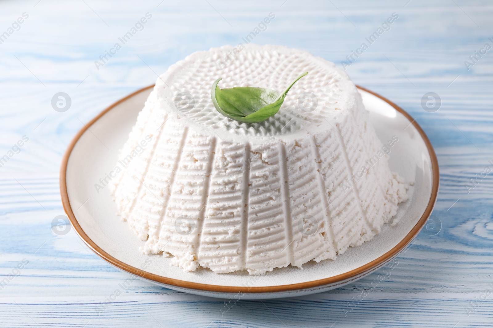 Photo of Tasty ricotta (cream cheese) on light blue wooden table