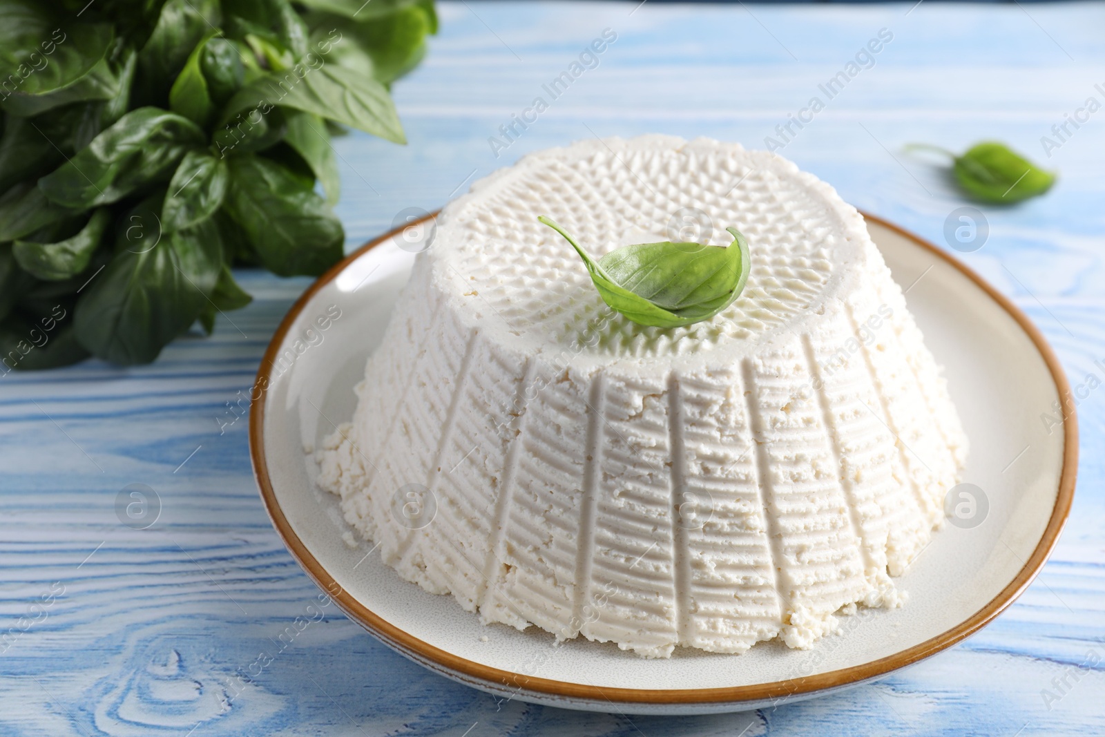 Photo of Tasty ricotta (cream cheese) on light blue wooden table