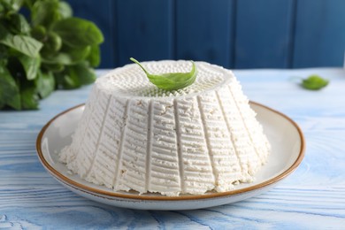 Photo of Tasty ricotta (cream cheese) on light blue wooden table