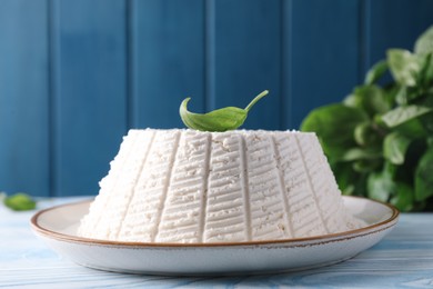 Photo of Tasty ricotta (cream cheese) on light blue wooden table, closeup