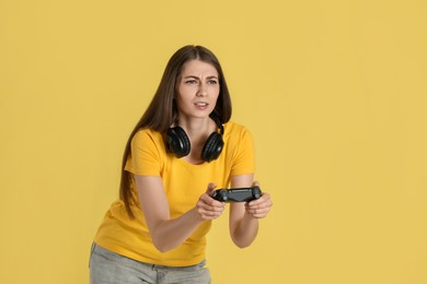 Woman playing video games with controller on yellow background