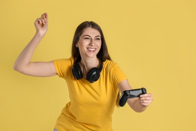 Photo of Happy woman playing video games with controller on yellow background