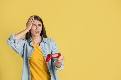 Photo of Unhappy woman playing video games with controller on yellow background, space for text