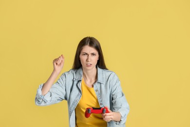 Photo of Woman playing video games with controller on yellow background