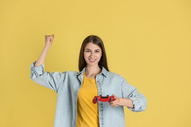 Happy woman with controller on yellow background